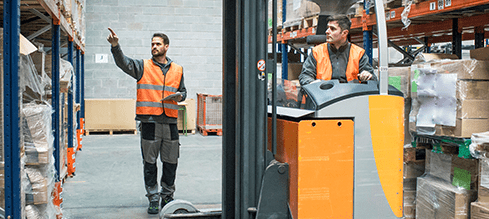 Two warehouse workers placing packages with a forklift